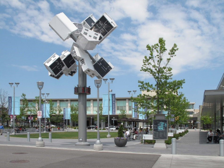 Installation of houses askew atop a pole in a park.