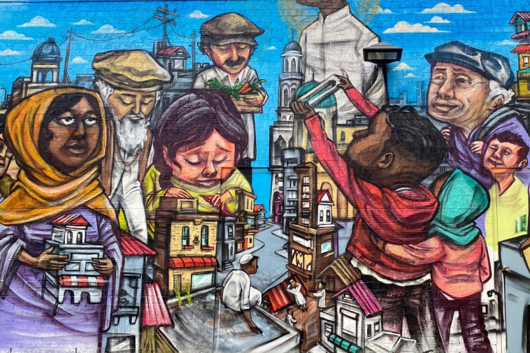 Mural of diverse people holding or surrounded by small buildings