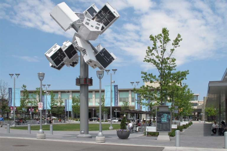 Installation of houses askew atop a pole in a park.