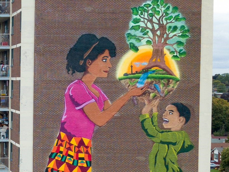 Mural of a little kid and their mother holding a tree with the silhouette of the Toronto skyline