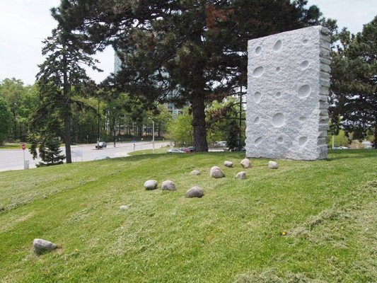 Installation of granite with scattered stones and a large stone rectangle standing upright